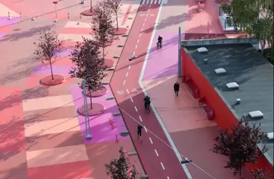 Vista aérea de la plaza roja de Superkilen, atravesada por una ciclovía, con árboles y personas en bicicleta.
