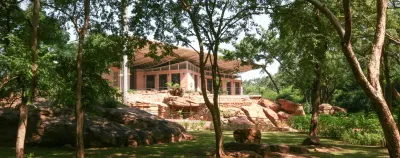 Pabellón de techo liviano entre árboles y grandes rocas en el Parque Nacional de Mali, en Bamako, de Francis Kéré.